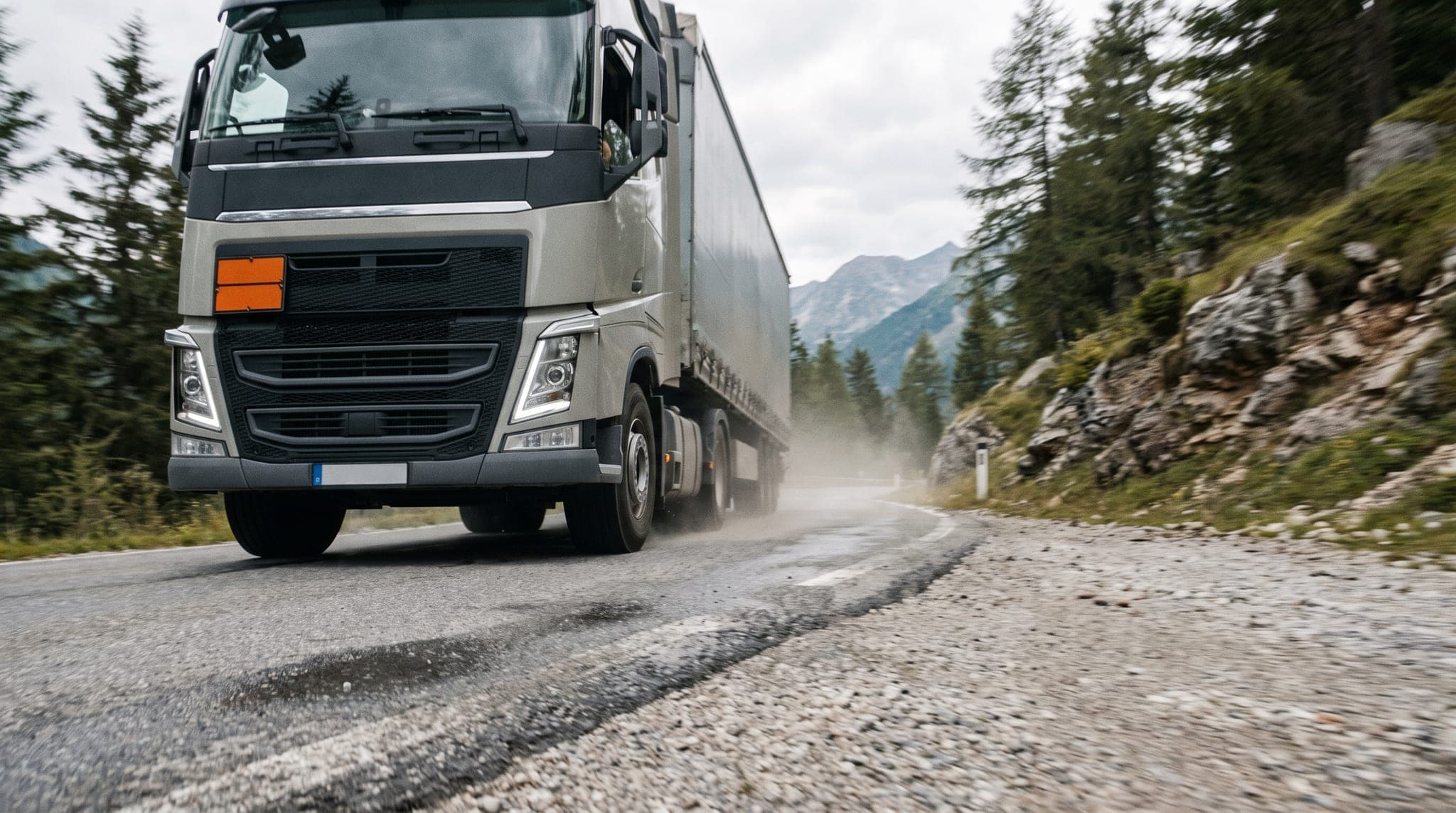 European truck with an orange ADR plate on an alpine highway at golden hour